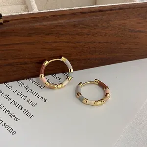 Detail of 14k gold plated hoop earrings with segmented colorful enamel drip