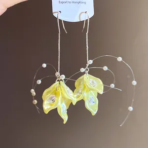 Detailed shot of yellow flower petal earrings featuring zirconia and pearl tassels