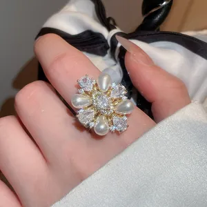 Nahaufnahme eines eleganten vergoldeten Rings mit Perlen und Zirkonia am Finger