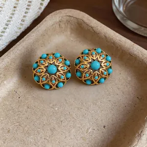 Detailed macro view of vintage 18k gold plated hollow flower earrings with turquoise beads.