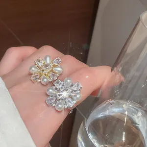 Nahaufnahme eines Blumenrings mit Zirkonia und tropfenförmigen Perlen in Goldoptik.