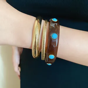 Close-up of retro resin and gold bangles set with turquoise studs on a woman's wrist