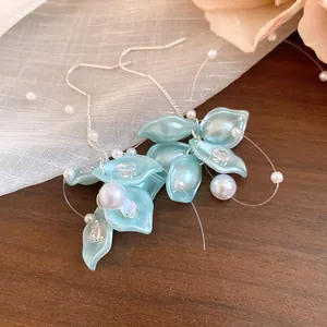 Close-up detail of sweet zircon petal and pearl tassel earrings on a rustic wooden surface.