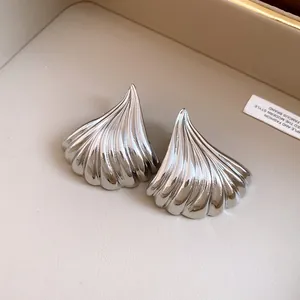 Dettaglio degli orecchini in metallo color argento con trama a ventaglio pieghettato.
