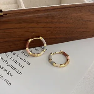 Close-up of 14k gold plated hoop earrings with colorful enamel bamboo segments.