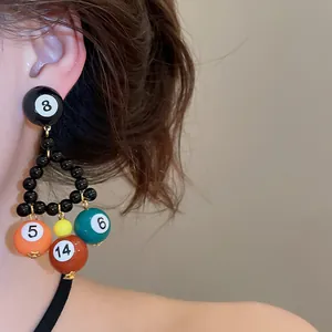Close-up of a unique colorful billiard ball triangle beaded earring being worn on an ear