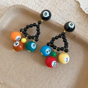 Detailed view of colorful mini pool ball charms on black beaded triangle earrings