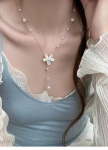 Detailed close-up showing zircon flower pendant and elegant pearl bead necklace on model