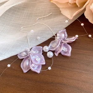 Macro view of purple petal drop earrings with zircon and pearls on gauze backdrop