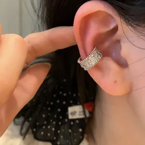 Detailed view of silver ear cuff encrusted with crystals featuring a gold clover motif