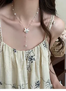 Detailed view of an elegant silver beaded pearl necklace with a shimmering zircon flower pendant