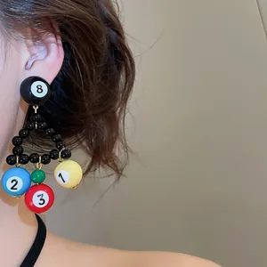 Close-up of niche design billiard ball beaded triangle drop earrings on a model.