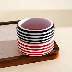 Detalle de brazaletes de resina a rayas rojas y negras en una bandeja de madera