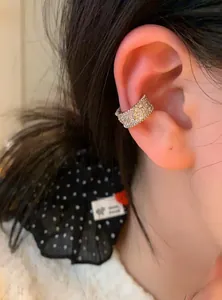 Macro view of a luxury clover motif ear cuff decorated with pave-set shimmering crystals