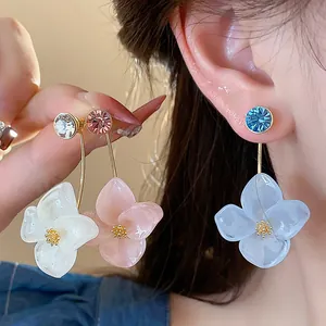 Detail of 18k gold-plated resin flower earrings in white, pink, and blue colors.