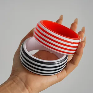 Vista detallada de brazaletes geométricos de resina con rayas rojas y negras a la moda