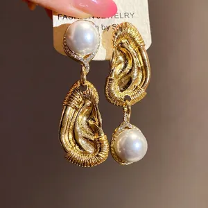 Vintage asymmetrische gold strukturierte Tropfenohrringe mit großen glänzenden Perlen.