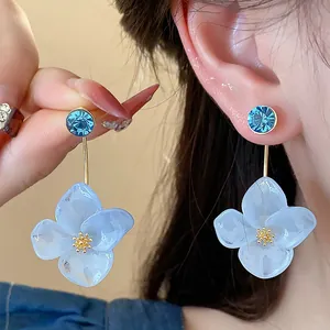Detailed close-up of elegant blue resin flower earrings with sparkling rhinestone studs