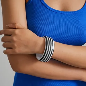 Primer plano de un brazalete de resina a rayas blancas y negras en la muñeca de un modelo