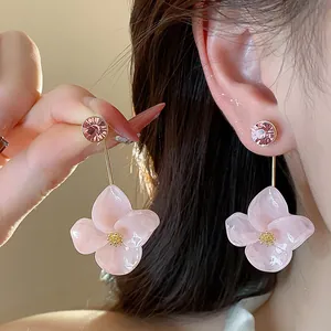 Detail showing pink resin flower drop earrings with rhinestone studs on ear.