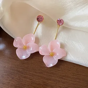 Close-up detail of pink resin flower earrings with gold-plated stems and rhinestones