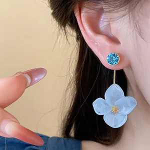 Detailed view of elegant light blue resin flower earrings with a shiny blue crystal