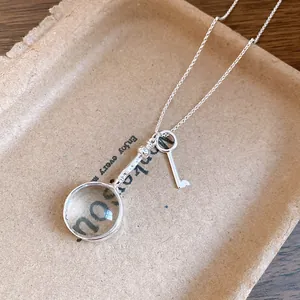 Detailed view of a vintage silver necklace featuring magnifying glass and key charms