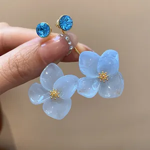 Detailed view of elegant light blue resin flower stud earrings with sparkling blue crystals