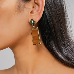 Detailansicht von Vintage-Goldohrringen mit grünem Edelstein und braunem Acetat.