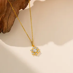 Gros plan d'un collier pendentif flocon de neige doré élégant avec des zircons étincelants.