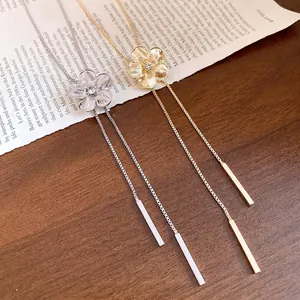Elegant rhinestone flower tassel necklace in gold and silver finishes on wood.