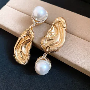 Nahaufnahme von goldenen Ohrringen im Vintage-Stil mit Perlen und Falten-Textur