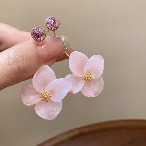 Detailed macro shot of 18k gold plated resin flower earrings with pink crystal studs