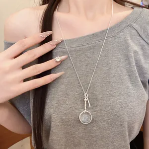 Close-up view of a vintage silver round magnifying glass key pendant necklace on model.