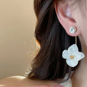 Close-up detail of a white resin flower earring with a sparkling crystal stud.