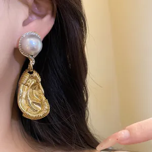 Detailansicht von Vintage-Goldohrringen mit Perle und strukturiertem Faltenanhänger.