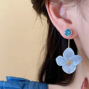 Close-up of elegant resin flower earring with blue rhinestone and gold-plated details.