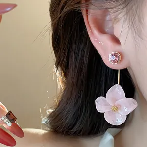 Close-up detail of 18k gold plated pink resin flower earring worn by a model