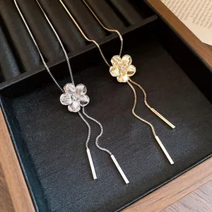 Close-up of gold and silver flower tassel necklaces with sparkling rhinestone centers.