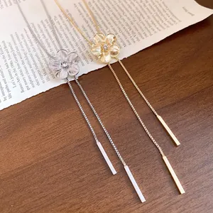 Elegant rhinestone flower tassel necklaces in gold and silver on an artistic background.