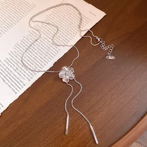 Elegant silver flower necklace detail with diamond center and long metal tassel pendants.