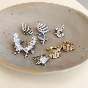 Eleganti earcuff con stelle in zircone e croce in un piatto di ceramica minimalista