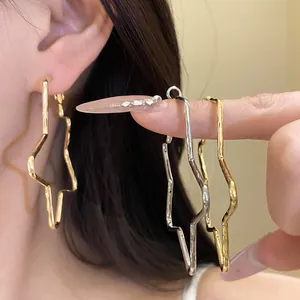 Detailed close-up of 18k gold plated star hoop earrings with hammered texture