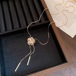Detail shot of a gold-tone floral pendant necklace with crystal and tassel elements.