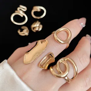 Fashionable gold chunky oval cross-wrapped rings presented on hand with macro detail