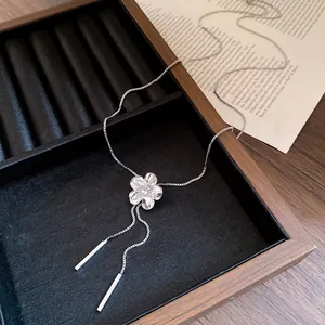 Detail shot of silver flower tassel necklace with rhinestone center in a jewelry box.