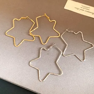 Detailed view of oversized star-shaped hoop earrings in gold and silver finishes