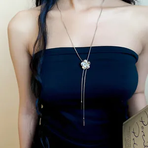 Detail view of a French luxury style silver floral tassel necklace on a black tube top