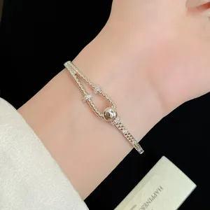 Detailaufnahme eines 18K vergoldeten Knotenknoten-Armbands mit Zirkonia am Handgelenk.