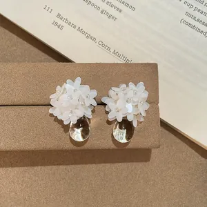 Detailaufnahme von weißen Harzblumen-Ohrringen mit klaren Wassertropfen-Anhängern